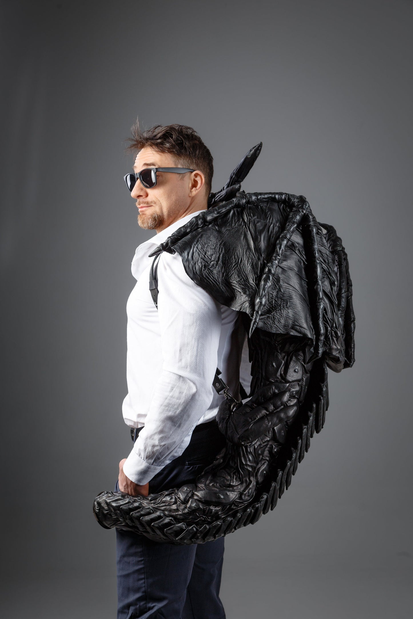 Leather dragon-backpack hugging you,  dragon tail wraps its around your waist, puts its paws on shoulders, covers your shoulders with wings